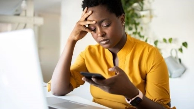 femme devant son ordinateur et son téléphone qui semble fatiguée